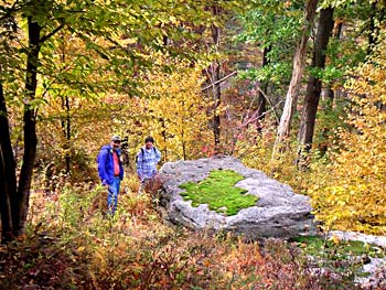 Two hikers by a bolder in the fall